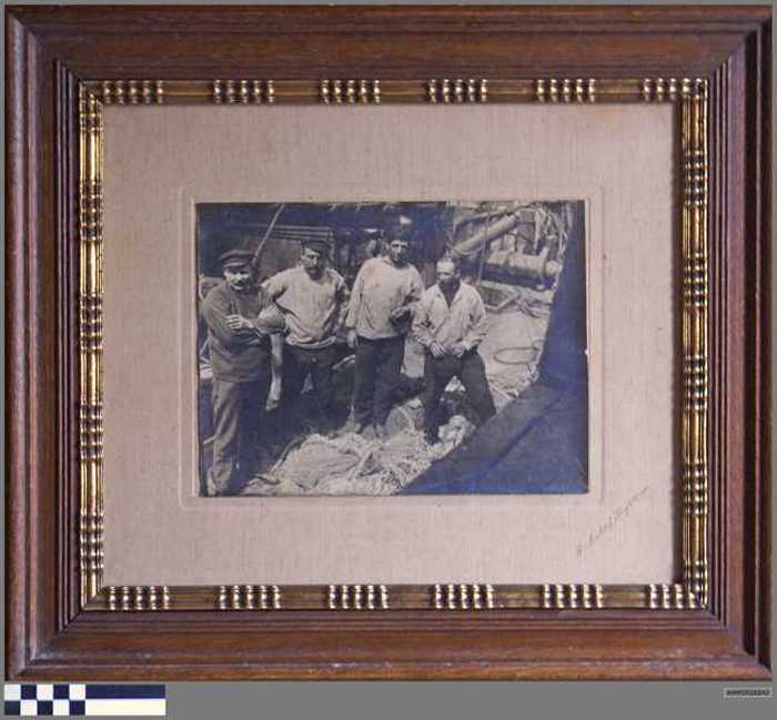 Groepsfoto vissers aan dek van een boot