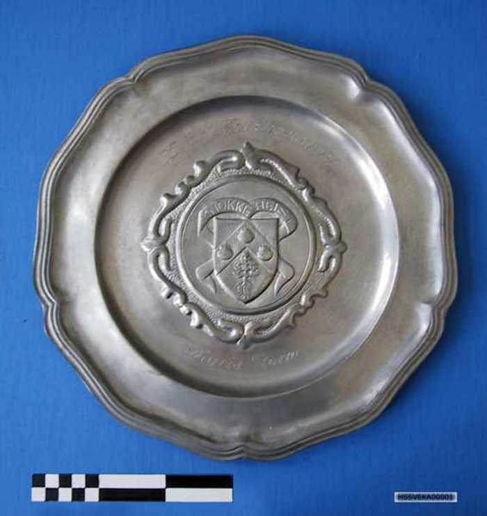 Sierbord in tin met schild van Knokke-Heist en inscriptie: `25 jaar Folkloremarkt - Maria Storm