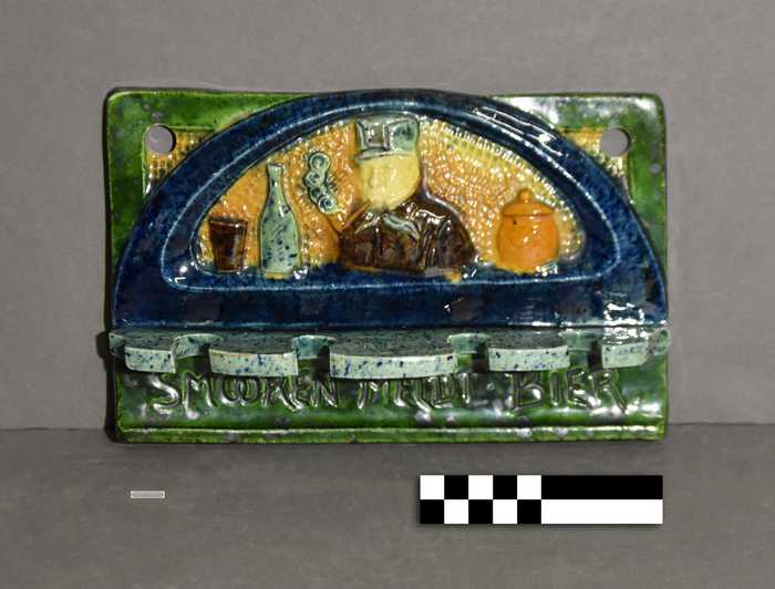 Pijpenhouder in Vlaams aardewerk in polychroom met opschrift 'Smooren meldt bier'