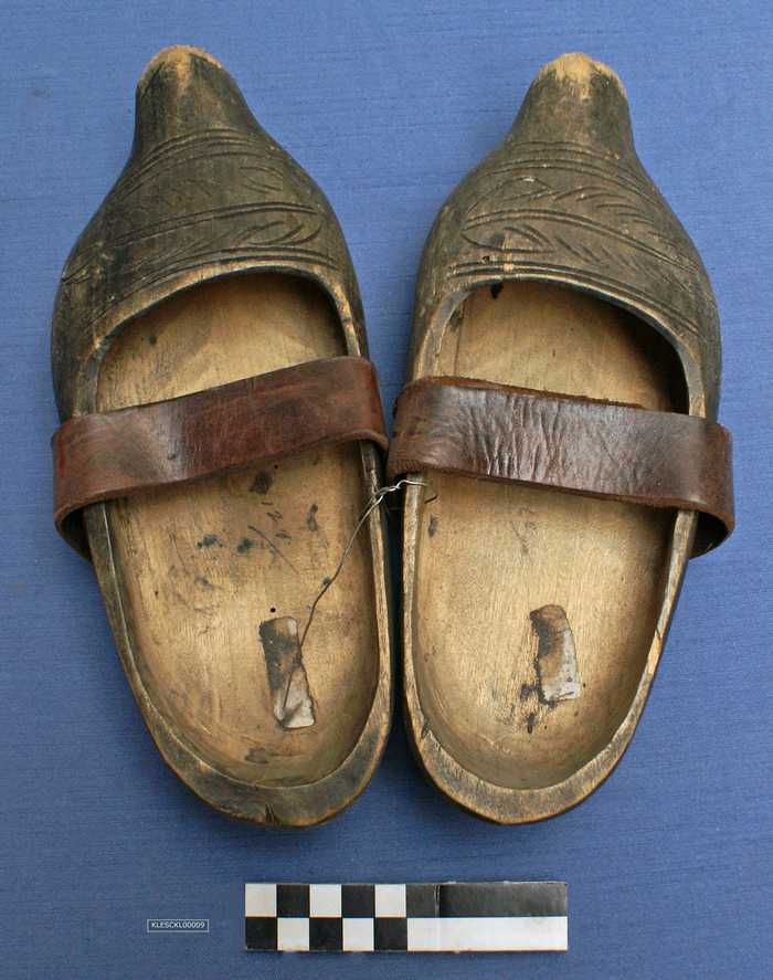 Paar zwarte klompen met bruine riemen